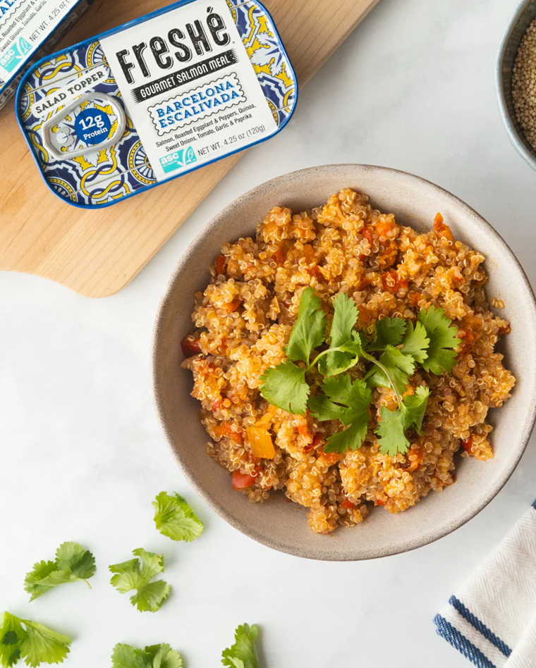 Bowl of Barcelona Escalivada salmon and quinoa topped with fresh cilantro, served beside a Freshé tin