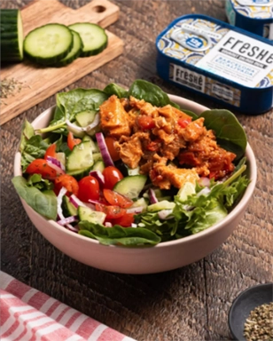 Salad with croutons and vegetables on a wooden table with Freshe packaging.