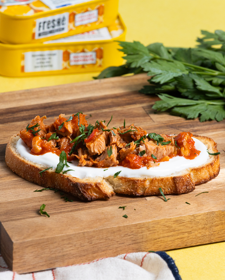 Tuna on toasted french bread on a wood cutting board